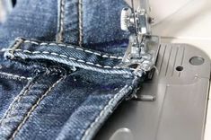 the sewing machine is stitching through jeans