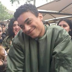 a man in a green shirt and tie standing next to a group of people with umbrellas