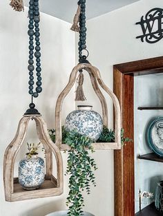 two hanging vases with plants in them and some decorations on the wall behind them