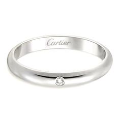 a white gold ring with a diamond in the center and an inscription on the side