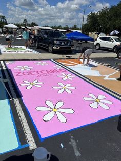 people are standing on the sidewalk painted with pink and white flowers, while others stand nearby