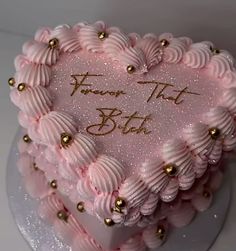 a heart shaped cake with pink frosting and gold decorations