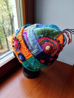 a multicolored hat sitting on top of a wooden table next to a window