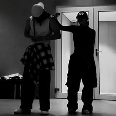 two men standing next to each other in front of a door with an object on it's head