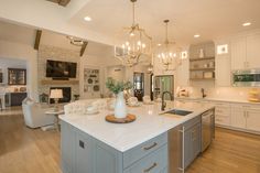 a large kitchen with an island and chandelier hanging from it's ceiling