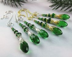 the green earrings are hanging from the christmas tree branch, and have gold - plated earwires