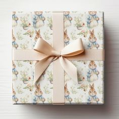 a wrapped gift box with a bow on it's side, sitting on a white surface