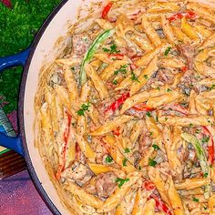 a pan filled with pasta and meat on top of a purple countertop next to vegetables