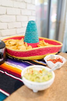 a table topped with bowls of food and a crock pot filled with guacamole