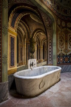 an old bathtub is in the middle of a room with ornate walls and arches