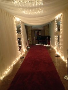 a red carpeted hallway with white drapes and lights on the ceiling is lit up