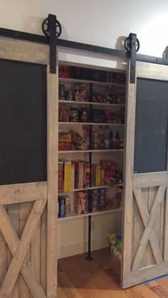 an open barn door with chalkboard on the side and sliding doors to reveal pantry area