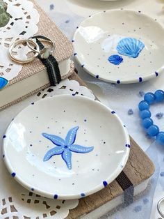 two white plates with blue starfish designs are sitting on a lace doily tablecloth