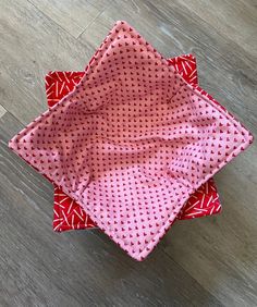 three pieces of red and white fabric sitting on top of a wooden floor next to each other