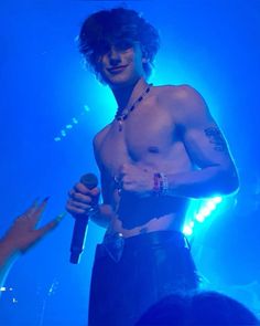 a shirtless man holding a microphone on stage