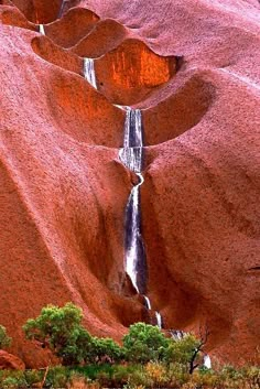 the water is running down the side of the rock formation, and there are many trees in the foreground