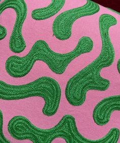 a pink and green fabric with wavy lines on it's back side, in the shape of an abstract design