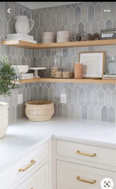 the shelves in this kitchen are made out of wood and white tiles with gold handles