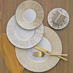 white and gold plates stacked on top of each other with golden forks next to them