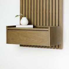 a white vase sitting on top of a wooden shelf next to a wall mounted shelf