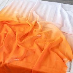 an orange and white blanket laying on top of a bed