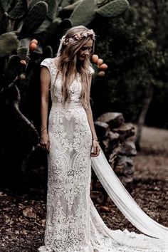 a woman wearing a wedding dress standing in the woods