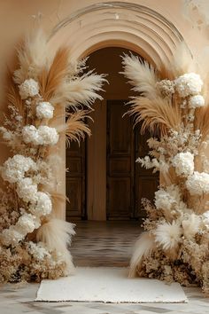 an archway decorated with white flowers and feathers