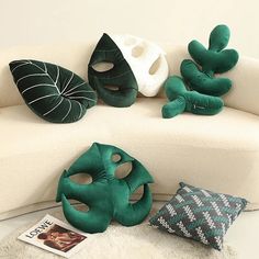 three green and white masks sitting on top of a couch next to two pillow pillows