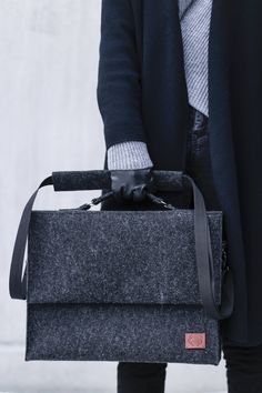 a person holding a briefcase in their hand and wearing a coat over the top of it