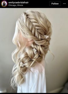 a woman with long blonde hair in a half up braid and some flowers on her head