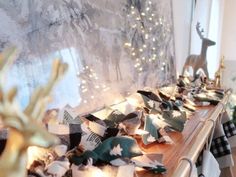 a wooden table topped with lots of paper flowers and deer figurines next to a window