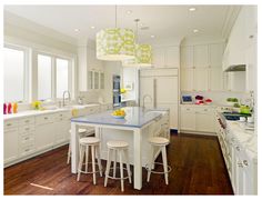 a large kitchen with white cabinets and blue counter tops on the island in front of two stools