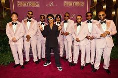 a group of men in pink tuxedos pose for a photo on the red carpet