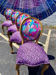 three purple chairs with leopard print upholstered on them and an umbrella in the background