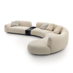 a curved couch with pillows on it and a coffee table in the middle for seating