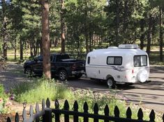 an rv is towing a black truck through the woods