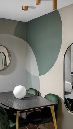 a dining room table with green chairs and a round mirror on the wall above it