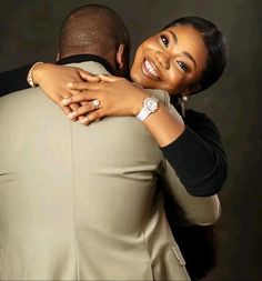 a man and woman hugging each other in front of a black background