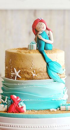 a cake with a little mermaid sitting on top of it