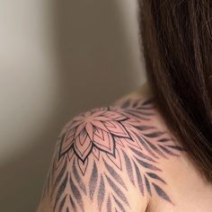 the back of a woman's shoulder with an intricate tattoo design on her arm