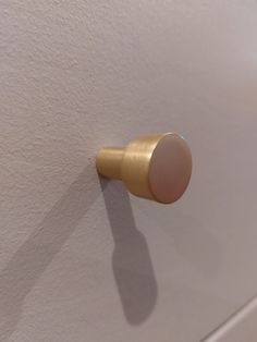 a door knob on the side of a white wall with a gold colored handle and an oval button