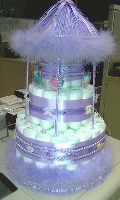 a purple and white diaper cake with an umbrella on it's top tier