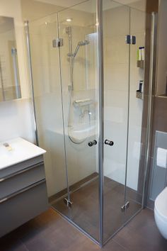 a bathroom with a stand up shower next to a white sink and toilet in it