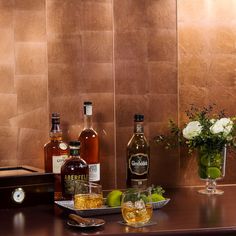 three bottles of alcohol sitting on top of a counter next to two glasses with ice