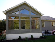 a house that is sitting in the grass with lots of windows on top of it