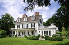 a large white house sitting on top of a lush green field