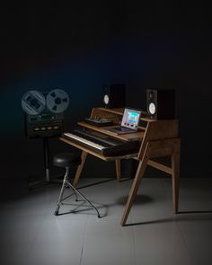 an electronic keyboard sitting on top of a wooden desk next to a monitor and speakers