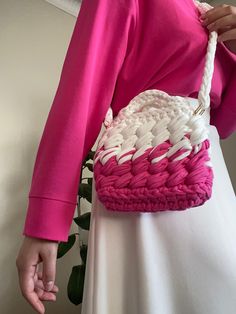 a woman is holding a pink and white basket