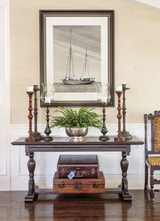 a room with a table, chairs and a painting on the wall above it that has a potted plant