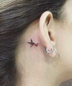 a woman with a small tattoo on her left side behind the ear that has a red heart in it